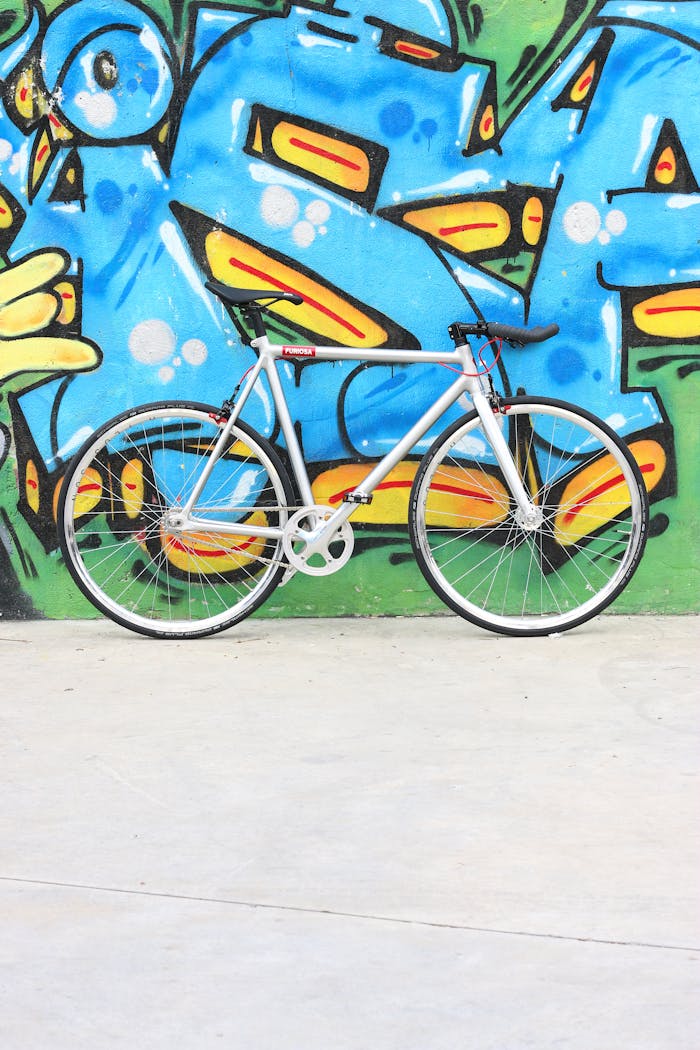 A stylish bike leaning against a vibrant graffiti mural, showcasing urban art.
