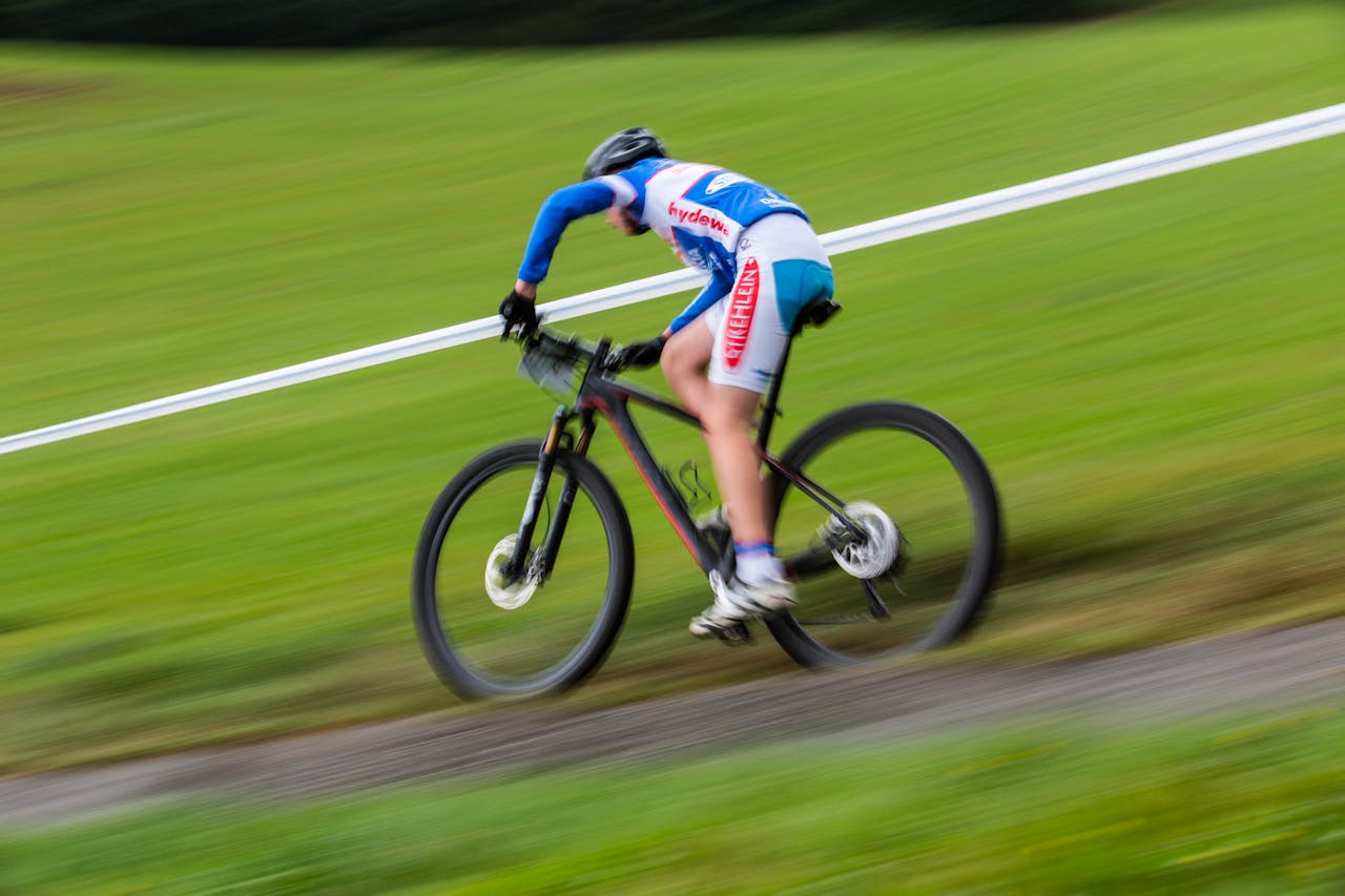 Cyclist racing downhill on a mountain bike at high speed outdoors.