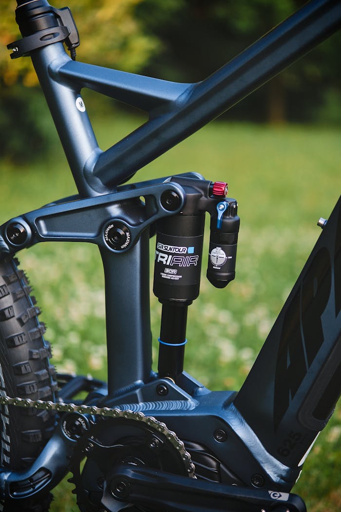 Detailed view of a bicycle suspension system in a green outdoor setting.